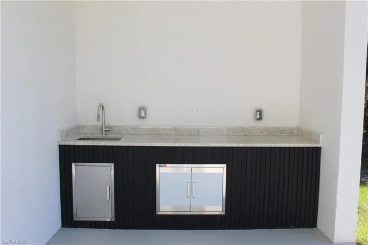 Bar featuring a sink and light stone countertops