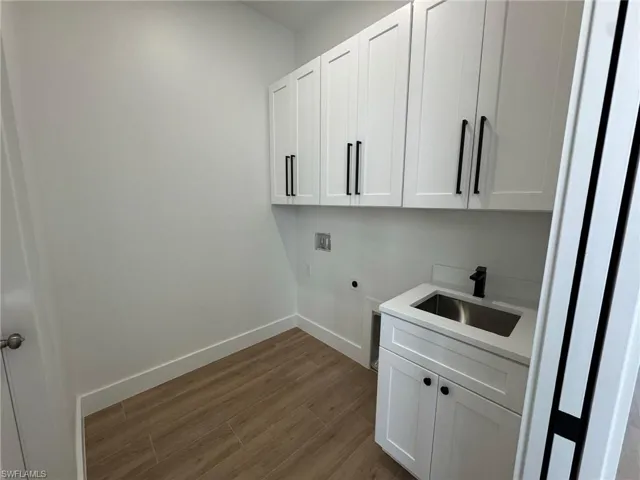 Laundry area with dark wood-style flooring, cabinet space, hookup for an electric dryer, and hookup for a washing machine