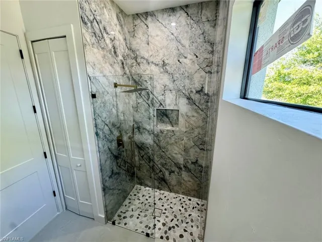 Full bath with a marble finish shower and a closet