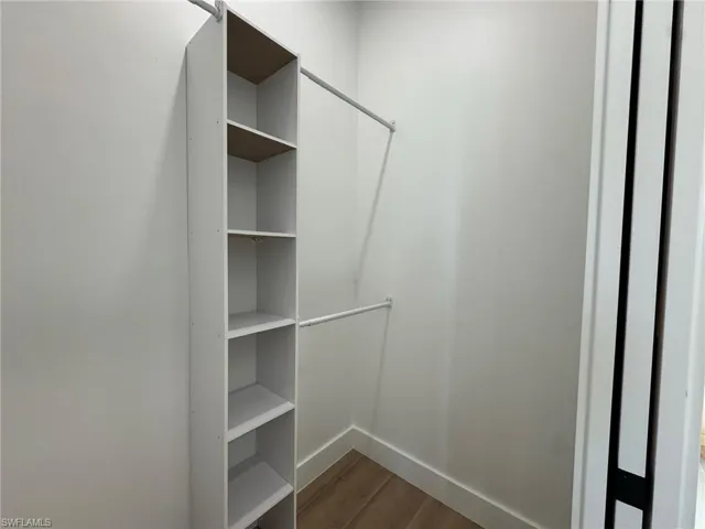 Walk in closet with dark wood-style flooring