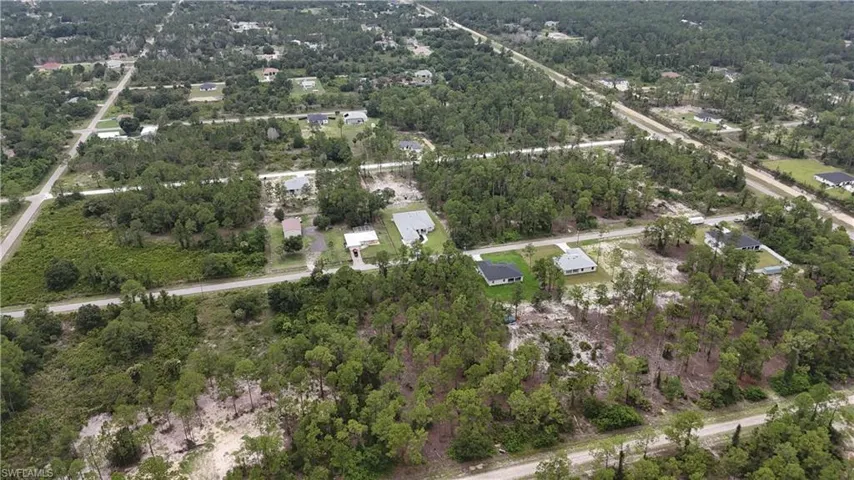 Aerial view showcasing multiple residential properties interspersed with undeveloped land
