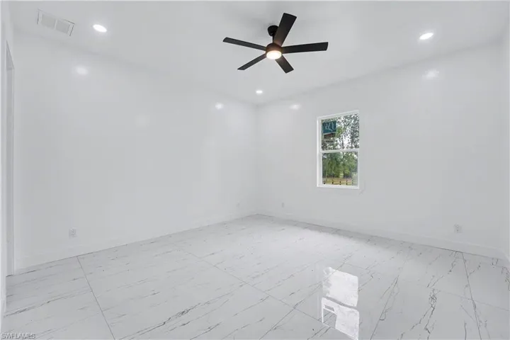 Spacious room featuring large format tile flooring, a contemporary ceiling fan with integrated lighting, recessed lighting, and a window with white trim
