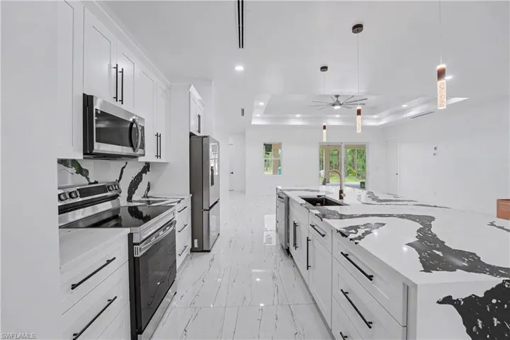 Modern kitchen featuring a large island with a waterfall edge, integrated sink, and sleek appliances