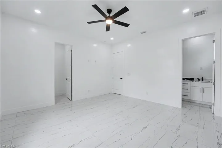 Spacious room featuring white walls and large format marble-look tile flooring