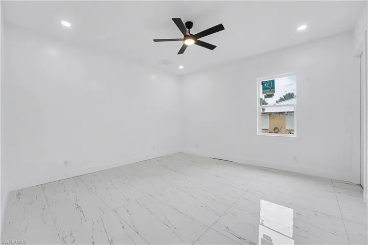 Spacious room featuring large format white tile flooring with grey veining, recessed lighting, and a modern black ceiling fan
