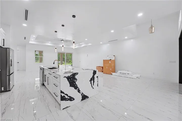 Open-concept living space with large format tile flooring and a prominent waterfall island featuring a striking black and white pattern