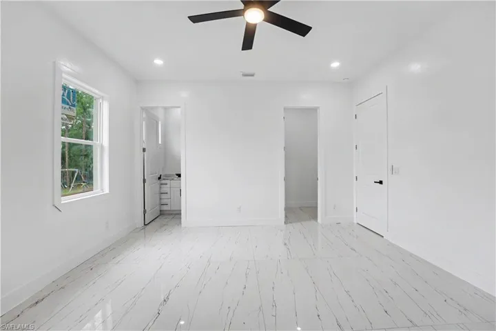 Spacious interior featuring marble-look tile flooring, white walls, and recessed lighting