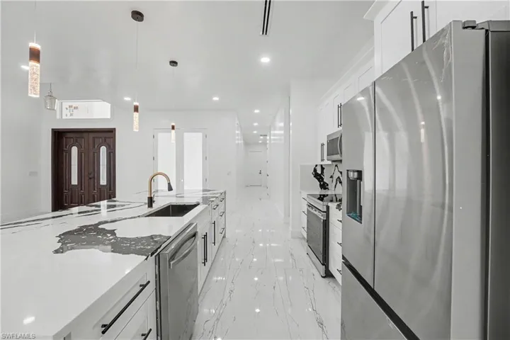 Modern kitchen featuring an expansive island with a waterfall countertop, integrated sink, and bronze-finish faucet