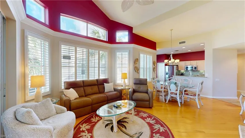 Living area with light hardwood floors, high vaulted ceiling, ceiling fan, and a chandelier