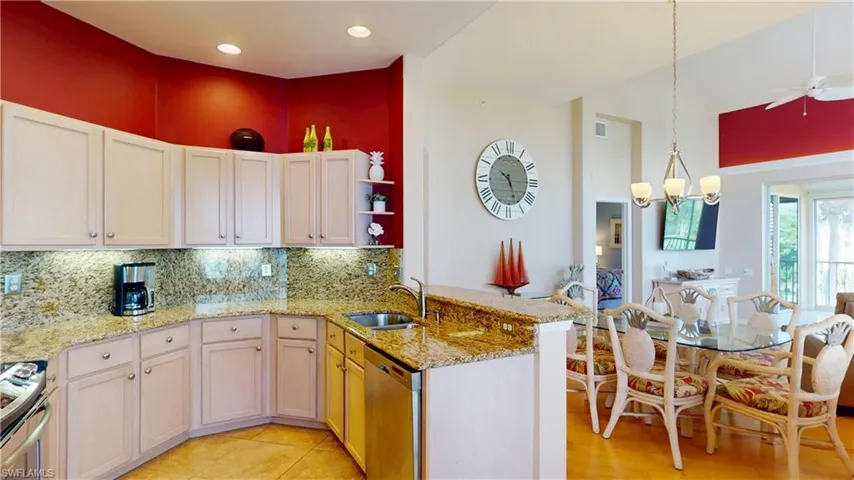 Kitchen with backsplash, a peninsula, appliances with stainless steel finishes, decorative light fixtures, and light stone countertops