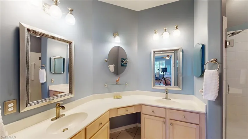 Primary Bathroom with double vanity, light tile patterned floors, and a stall shower