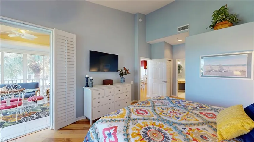 Primary Bedroom with light hardwood floors, access to exterior, a towering ceiling, ensuite bathroom, and a closet