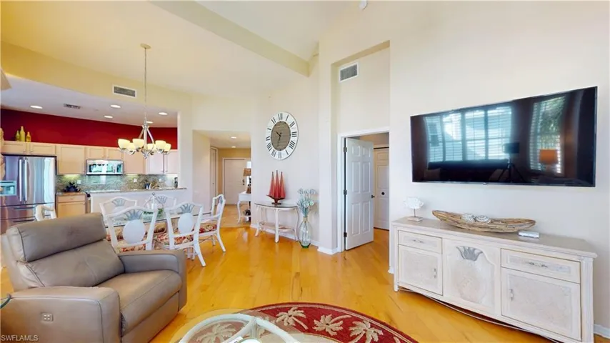 Living area featuring light hardwood floors, a chandelier, a towering ceiling, and recessed lighting
