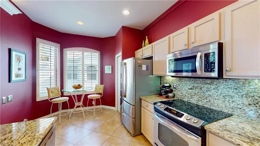 Kitchen featuring appliances with stainless steel finishes, light stone countertops, tasteful backsplash, light tile patterned floors, and recessed lighting