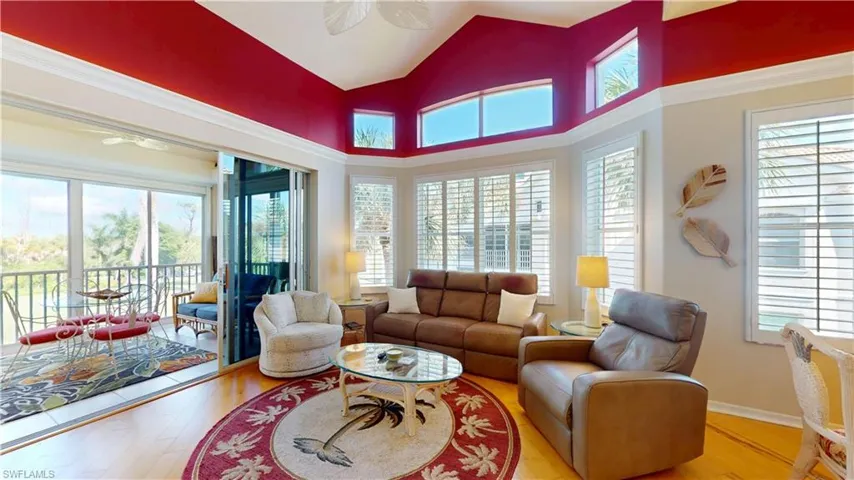 Living area with ceiling fan, hardwood floors, and high vaulted ceiling