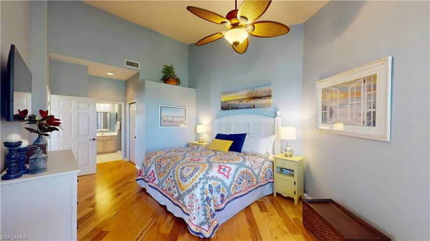 Primary Bedroom featuring light hardwood flooring, ceiling fan, ensuite bathroom, a high ceiling, and a closet