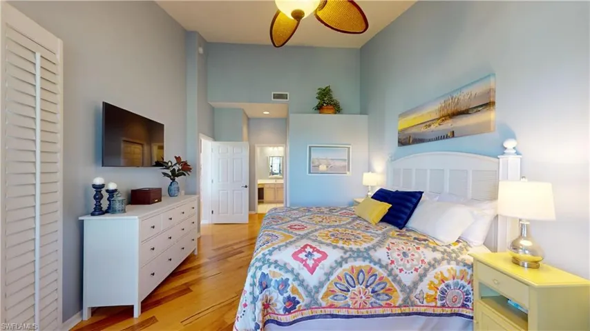 Primary Bedroom with ensuite bath, a high ceiling, and light hardwood floors