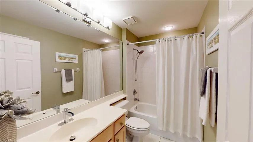 Bathroom with vanity, shower / tub combo with curtain, and light tile patterned floors