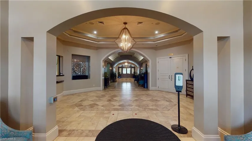 Entryway with a chandelier, arched walkways, a tray ceiling, crown molding, and recessed lighting