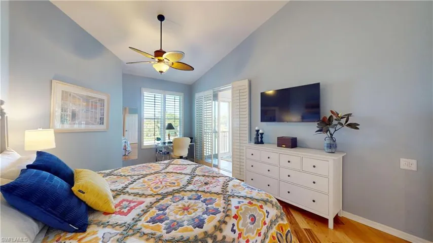 Primary Bedroom featuring light hardwood flooring, vaulted ceiling, access to exterior, and ceiling fan