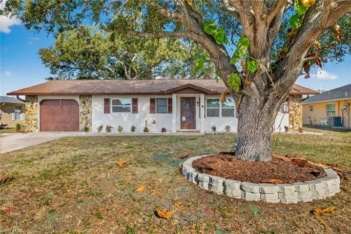 Ranch-style house featuring stone siding, an attached garage, driveway, and a front yard