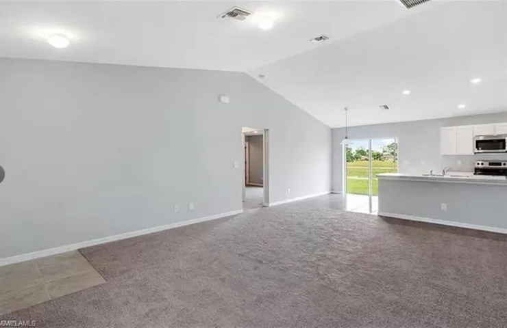 Living room with dark colored carpet and vaulted ceiling