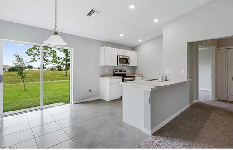 Kitchen with white cabinetry, stainless steel appliances, a peninsula, decorative light fixtures, and light tile patterned floors