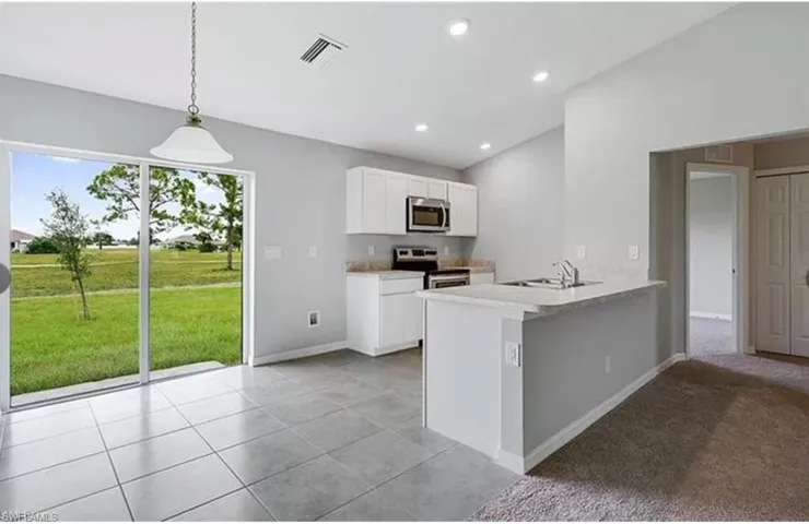 Kitchen featuring white cabinets, stainless steel appliances, a peninsula, decorative light fixtures, and recessed lighting