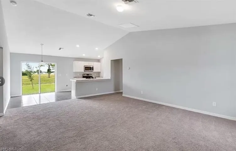 Unfurnished living room with vaulted ceiling, light colored carpet, and recessed lighting