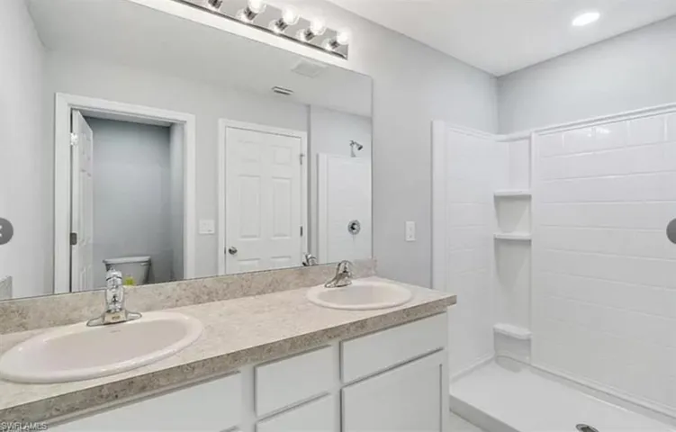 Bathroom featuring double vanity and tiled shower