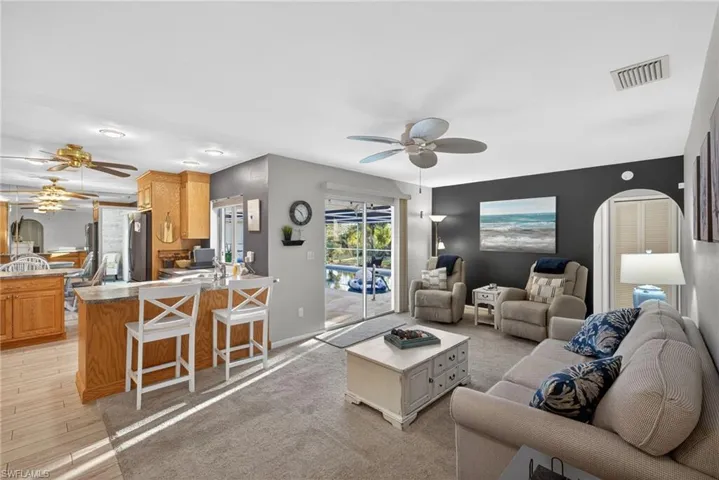Living room featuring a ceiling fan, an accent wall, light wood finished floors, and arched walkways