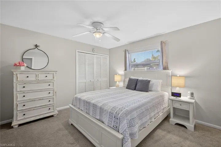 Bedroom featuring a ceiling fan, light colored carpet, and a closet