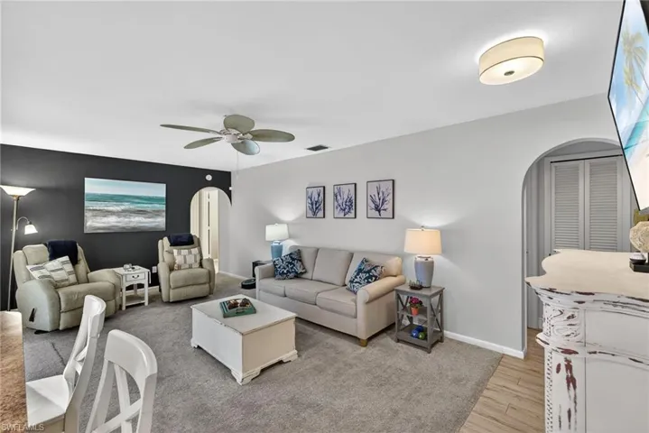 Living room with arched walkways, ceiling fan, and light wood finished floors