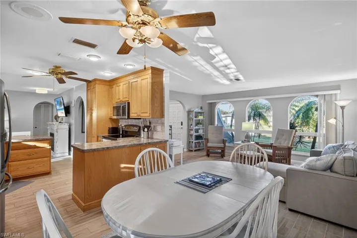 Dining room featuring arched walkways, a ceiling fan, and light wood-style flooring