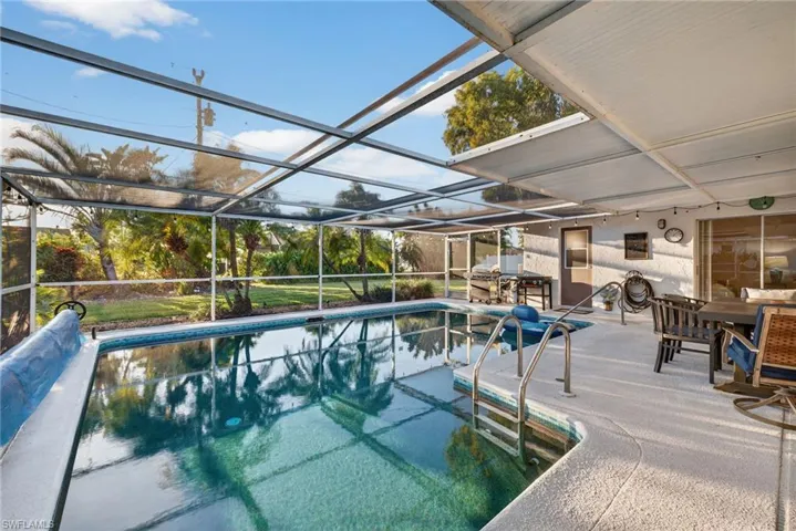 Outdoor pool with a sunroom, a patio, glass enclosure, and outdoor dining area
