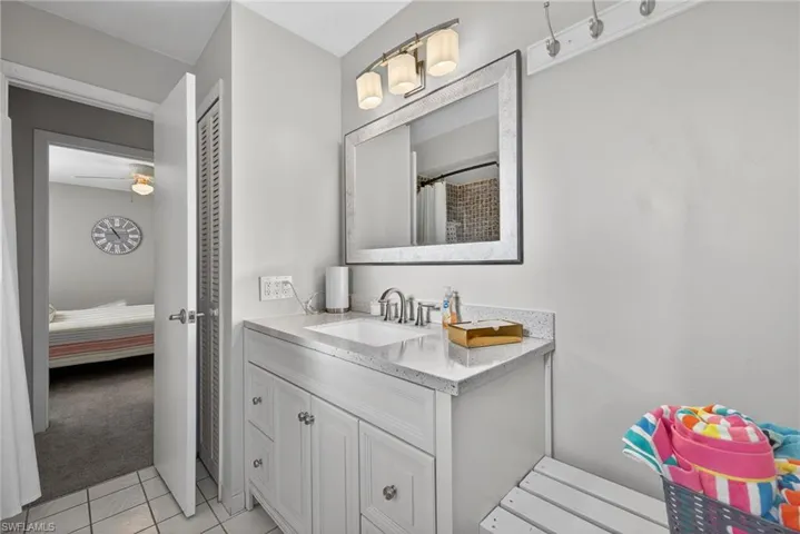Ensuite bathroom with vanity, light colored carpet, curtained shower, and light tile patterned floors