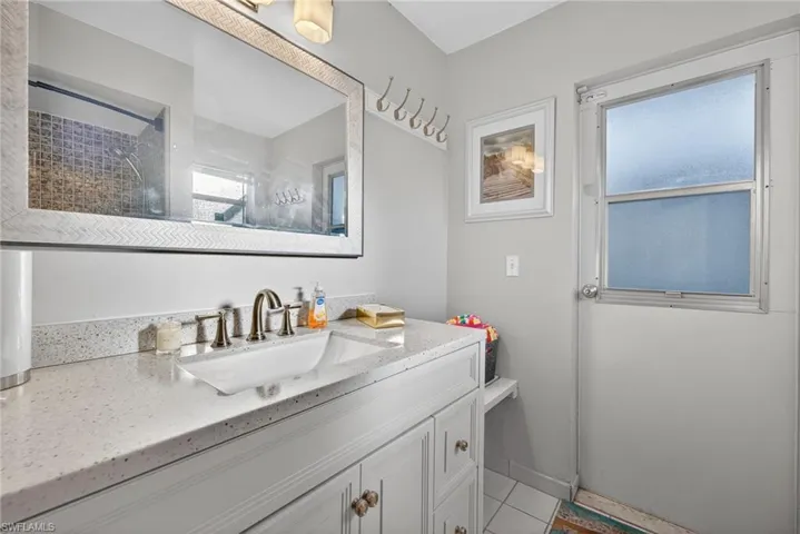 Bathroom with vanity, tiled shower, and light tile patterned flooring
