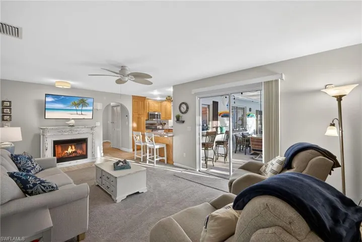Living area with arched walkways, a high end fireplace, a ceiling fan, and carpet floors