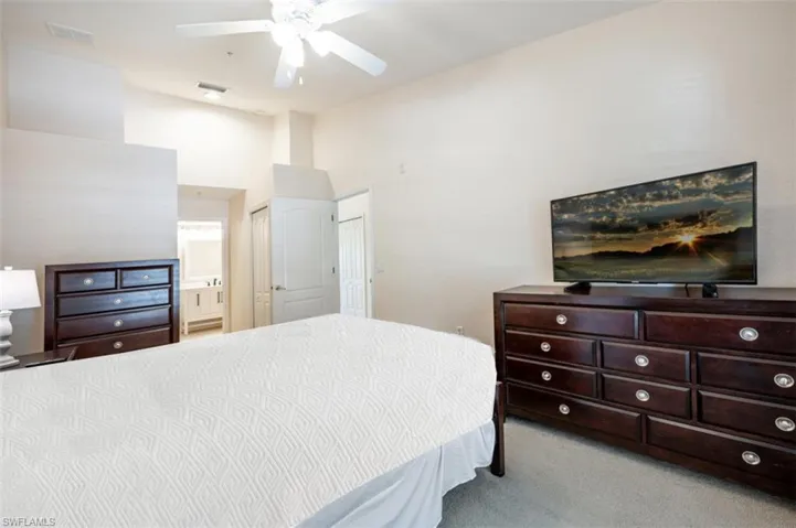 Carpeted bedroom with a towering ceiling, connected bathroom, a closet, and ceiling fan
