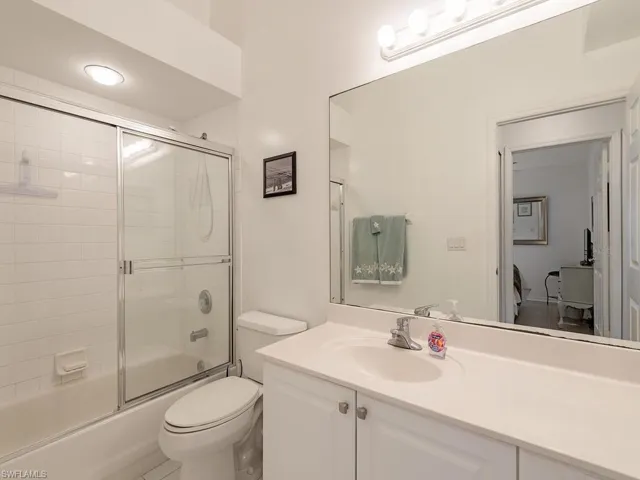 Full bathroom featuring shower / bath combination with glass door, vanity, and toilet