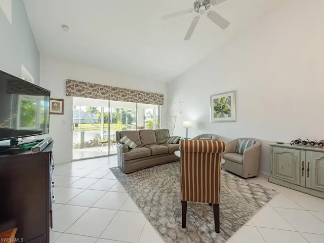 Living room with ceiling fan, light tile patterned flooring, and high vaulted ceiling