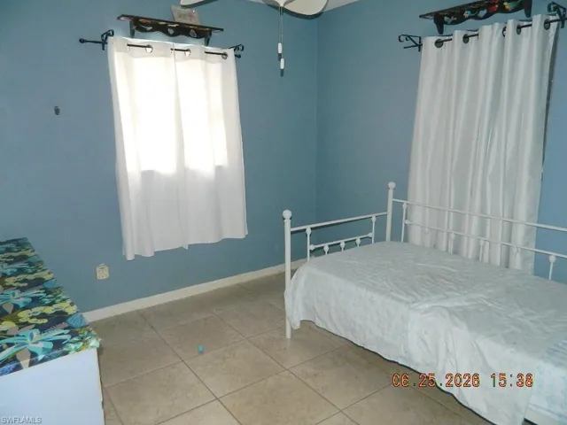 Room featuring light blue walls, tile flooring, and a single window with white drapery