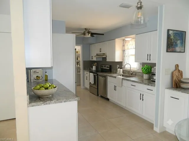 Virtually Staged. Well-appointed kitchen featuring white cabinetry, light-toned countertops, tile flooring, and stainless steel appliances