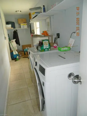 Laundry area featuring tile flooring, wall-mounted shelving, and a built-in hanging rod
