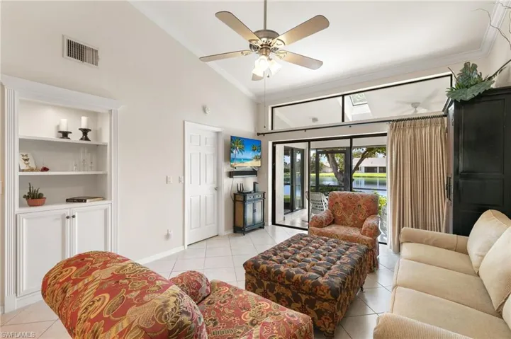 Living area featuring crown molding, a high ceiling, light tile patterned floors, ceiling fan, and a skylight