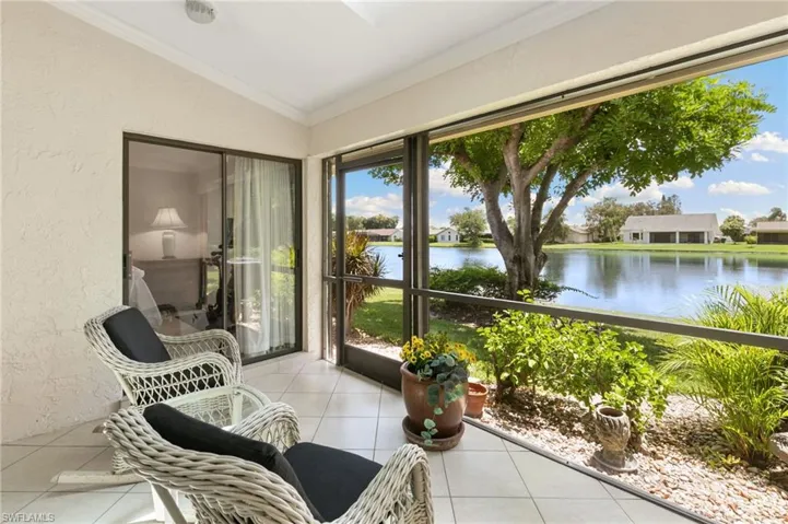 Sunroom with a textured wall, lofted ceiling, ornamental molding, tile patterned floors, and a water view