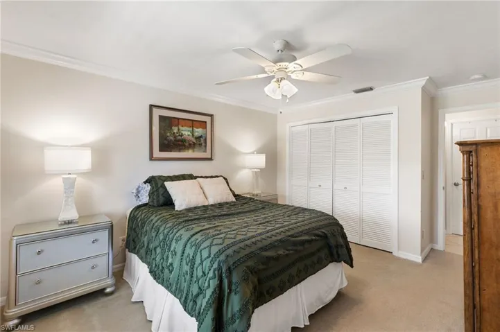 Bedroom with ornamental molding, light carpet, a closet, and ceiling fan