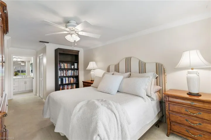 Carpeted bedroom with ornamental molding, ensuite bathroom, and ceiling fan