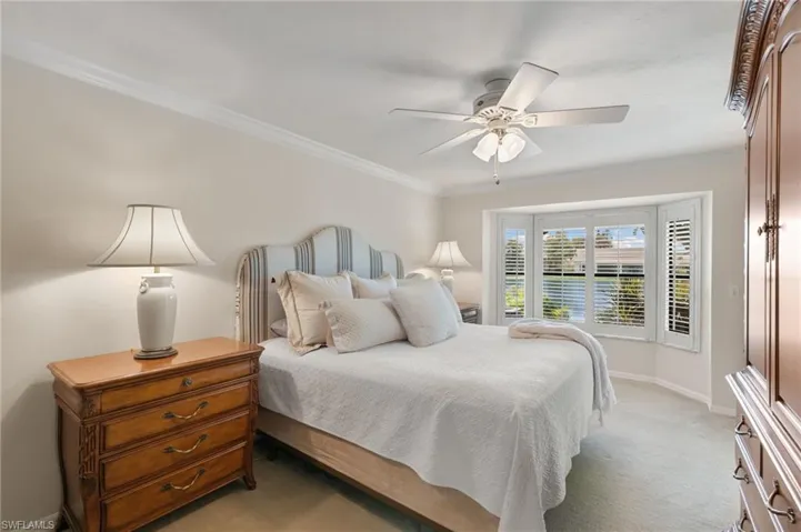 Bedroom featuring crown molding, light carpet, and a ceiling fan