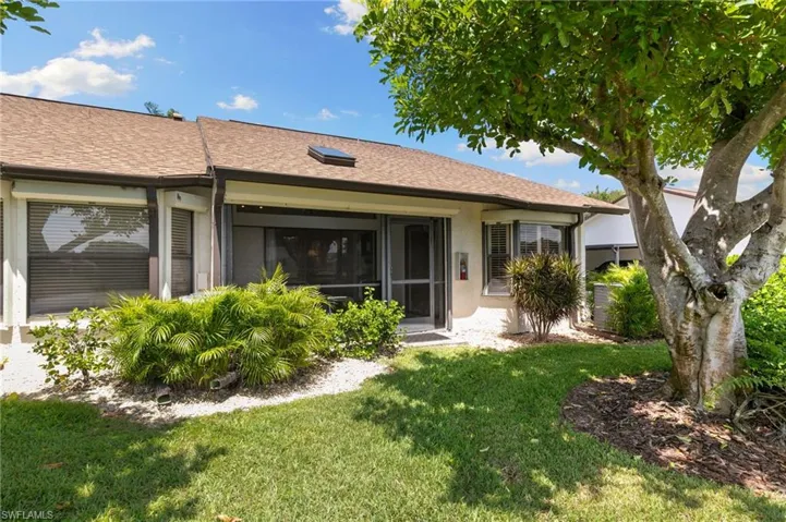 Rear view of property featuring a yard, stucco siding, a sunroom, and a shingled roof